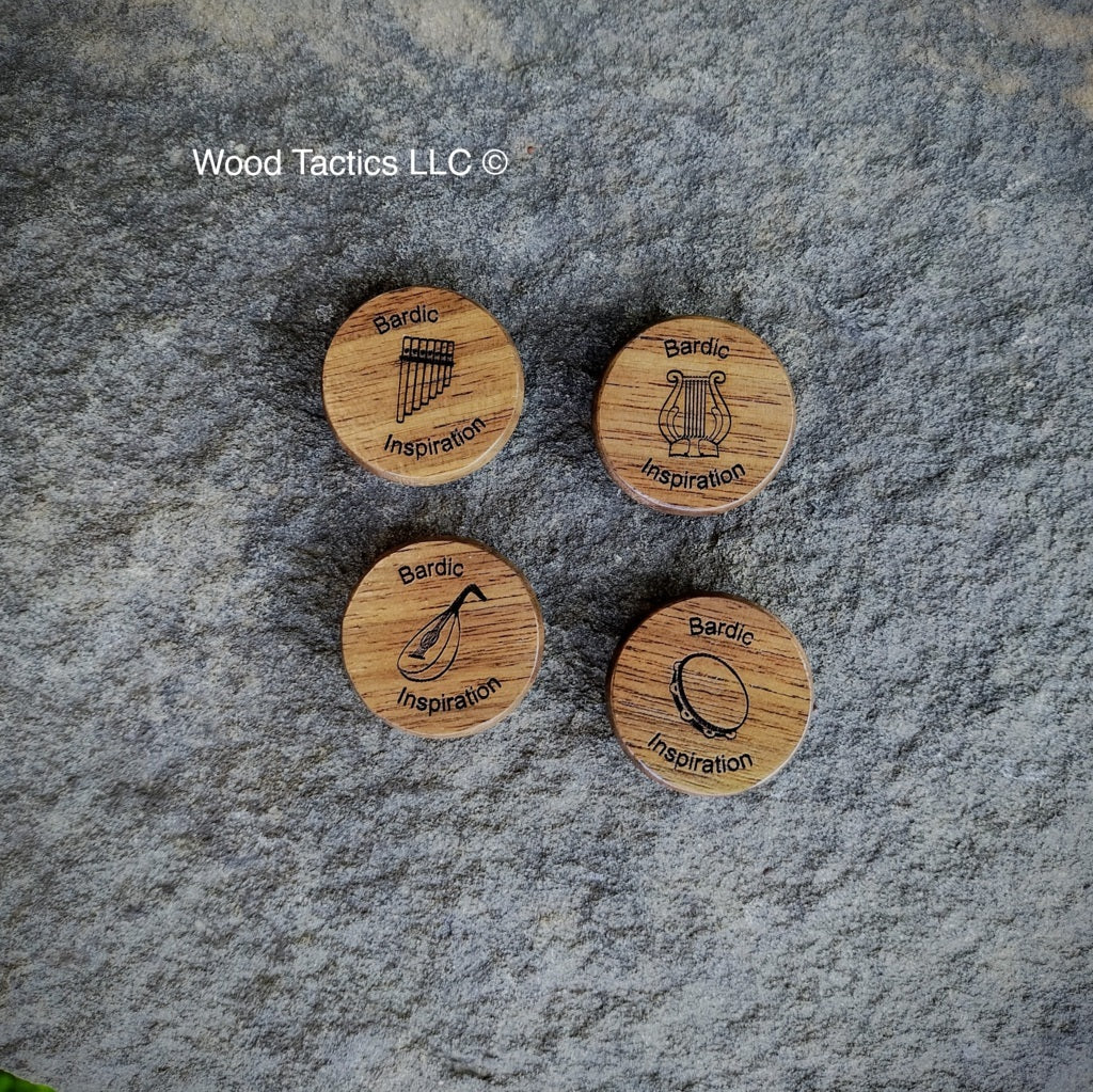 Four wooden tokens with engraved symbols and 'Bardic Inspiration' text on a stone surface